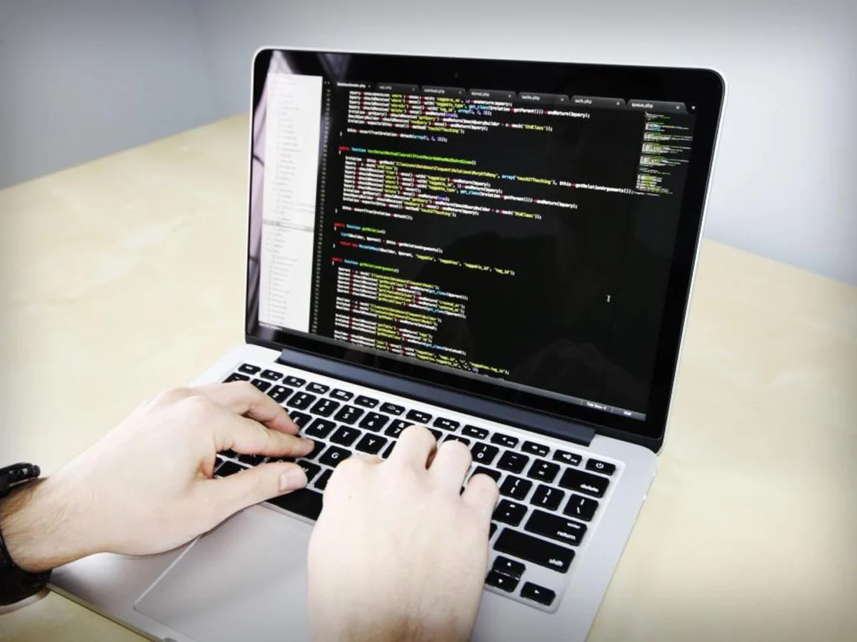 Hände tippen Code auf einem Laptop