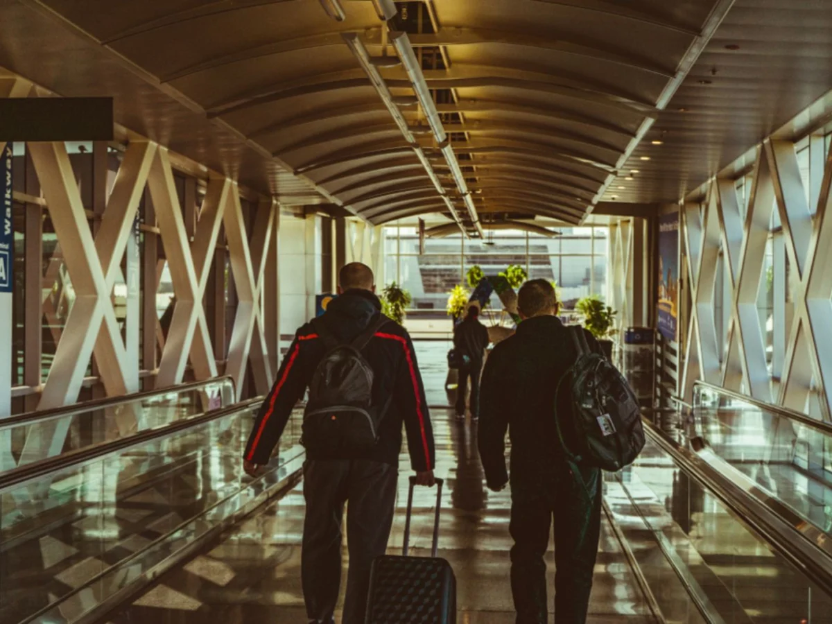 Reisende mit Gepäck auf dem Weg durch einen Flughafen